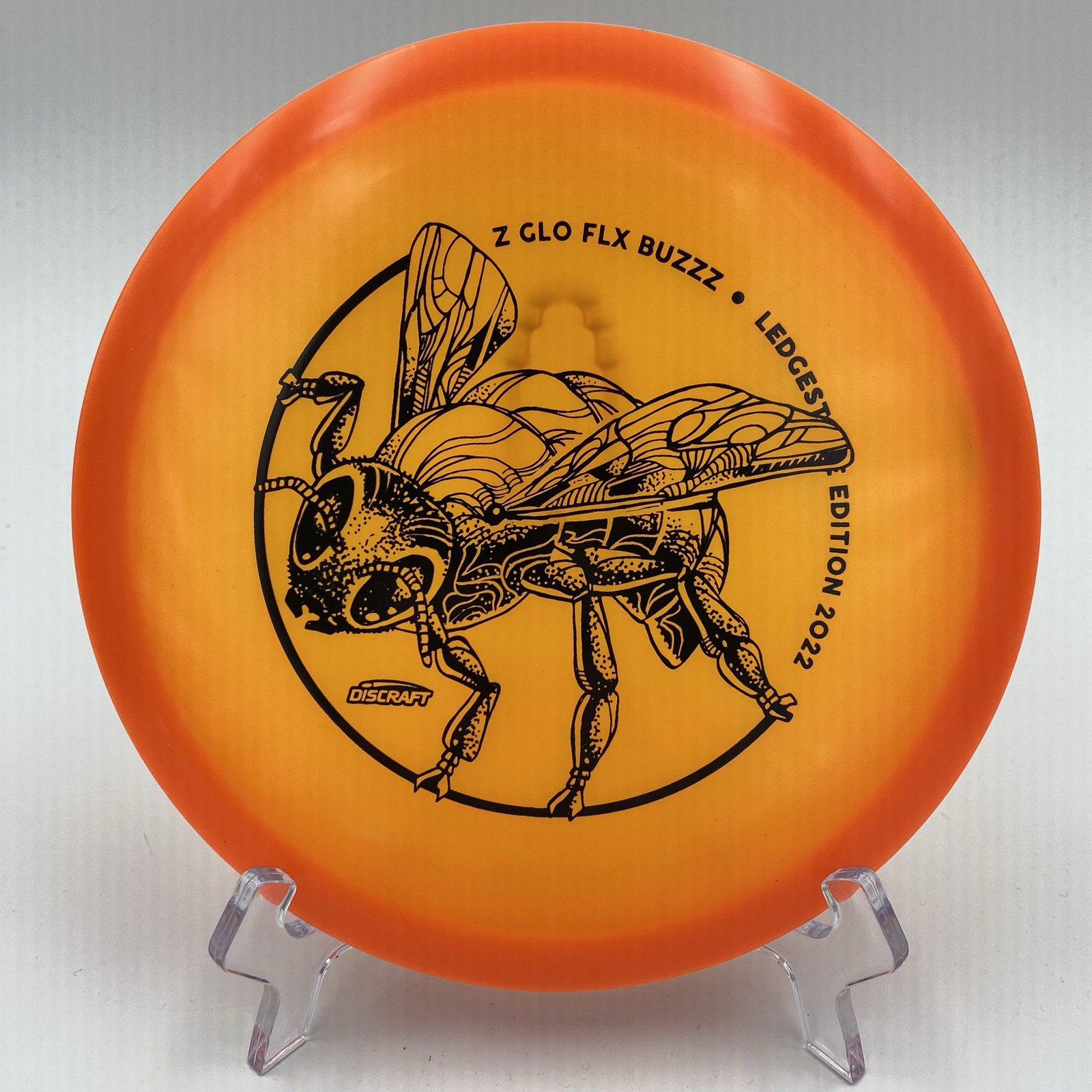 Top view of orange Discraft Z Glo FLX Buzzz in Ledgestone 2022 Edition with a stunning glow effect.