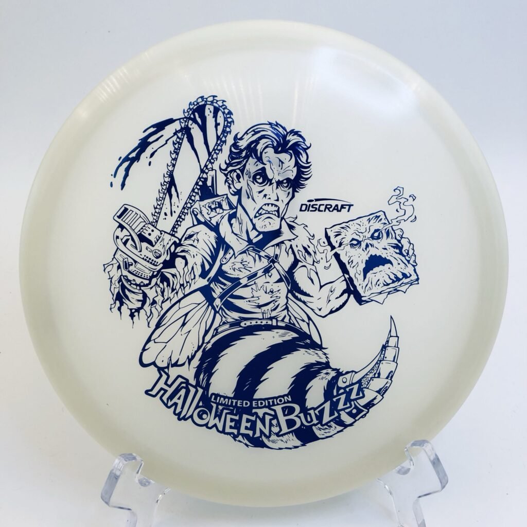Top view of glowing green Discraft Buzzz in Nite Glo plastic - 2023 Halloween Edition with vibrant artwork.